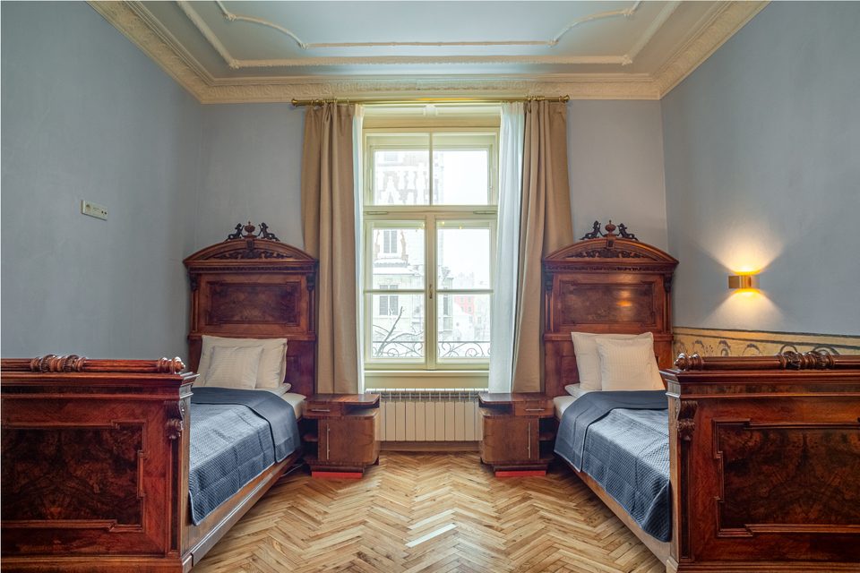 Dwa pojedyncze łóżka przy oknie z widokiem na Rynek
