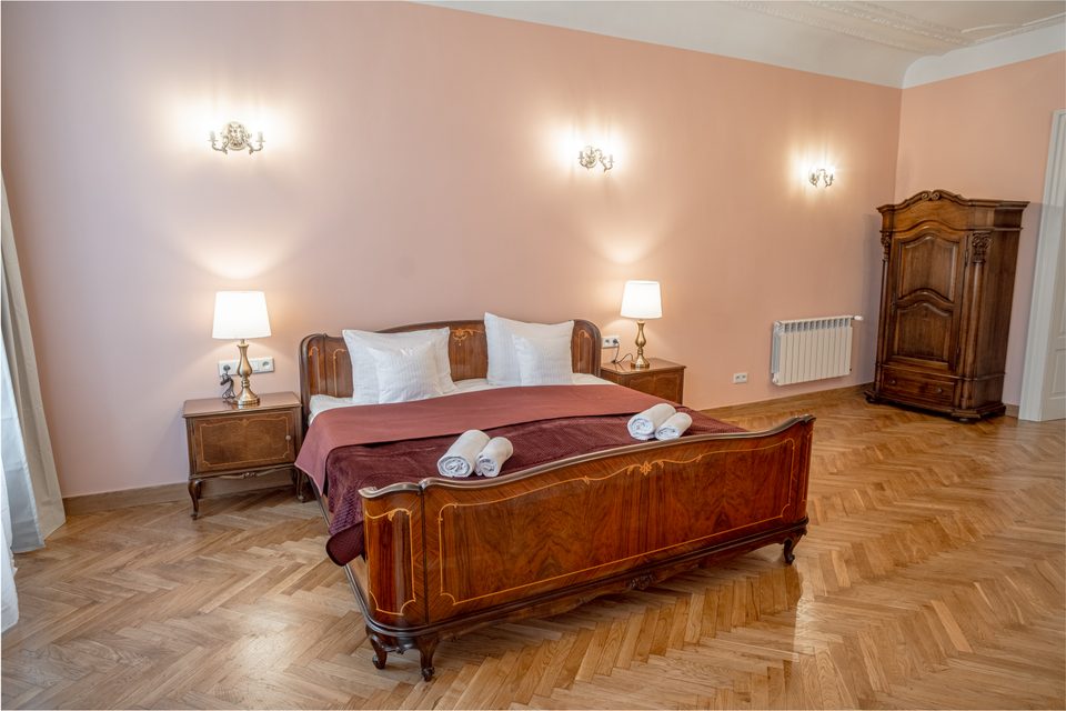Podwójne łóżko i zabytkowa szafa w apartamencie