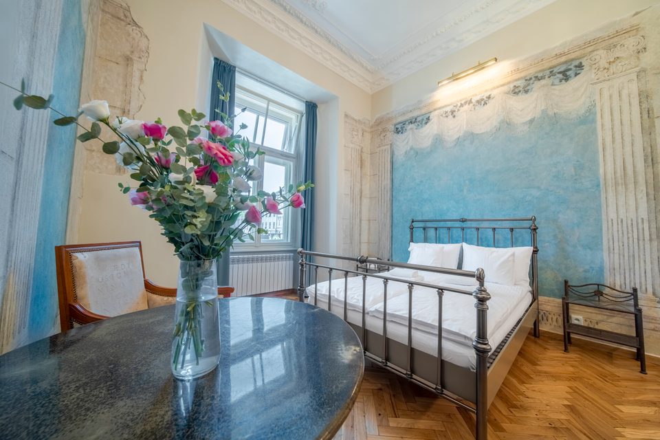 Sypialnia apartamentu z niebieskim freskiem i bukietem kwiatów
