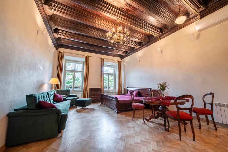 Przestronny apartament z drewnianym stropem i zieloną sofą